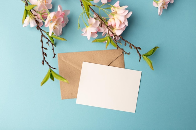 Envelopes artesanais folha de papel em branco e um raminho de magnólia sobre fundo azul