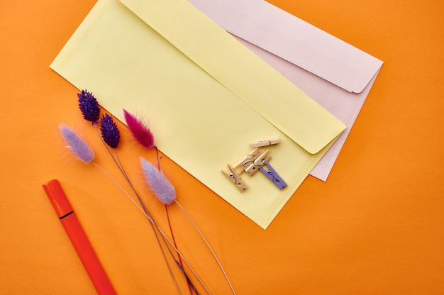 Envelopes postais e close up dos clipes de papel, fundo laranja. Material de papelaria para escritório, acessórios escolares ou educacionais, ferramentas de escrita e desenho