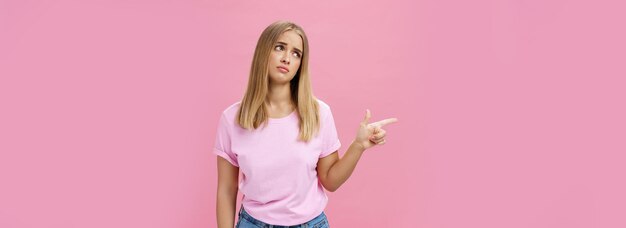 Foto envidia molesta linda joven europea con piel bronceada y pelo claro inclinando la cabeza levantando las cejas en persona