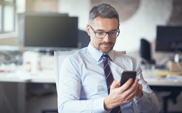 Y envíe una foto recortada de un hombre de negocios usando su teléfono celular mientras está sentado en su oficina