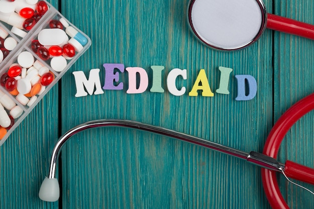 Envíe un mensaje de texto a Medicaid con estetoscopio y pastillas de letras de madera coloreadas
