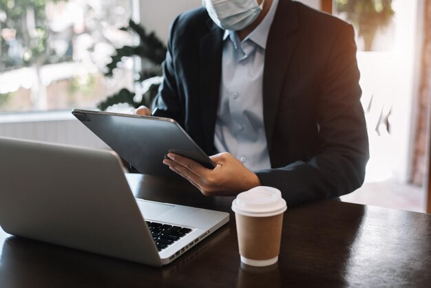 Envie uma mensagem a um colega um empresário confiante em combinar um tablet e sentado no escritório