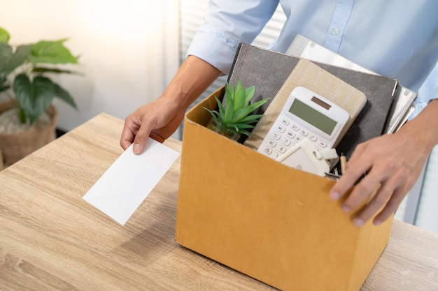 Envío de una carta de renuncia al jefe y retención de cosas Renuncia Deprimir o llevar una caja de cartón en el escritorio de la oficina