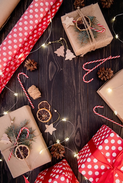 Envoltorio de cajas de regalo en papel artesanal decorado con piñas, bastones de caramelo y ramas de abeto