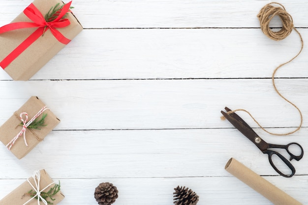 Envoltorio de regalo. Mano artesanal regalos de Navidad caja de regalos y herramientas sobre fondo de madera blanca. Disposición plana, composición de la vista superior, diseño del espacio de la copia.