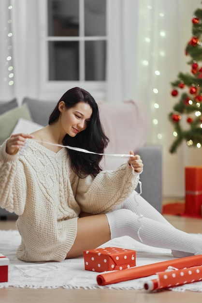 Envoltorio de regalo de Navidad y año nuevo por mujer en casa durante las vacaciones de invierno