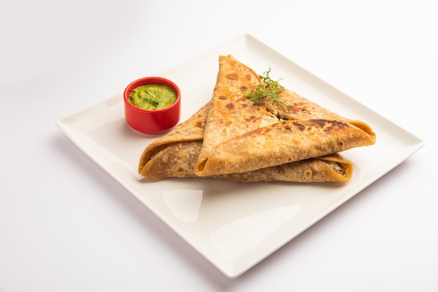 Envoltura triangular de Paratha con relleno de pollo a la patata, servido con chutney verde, comida india