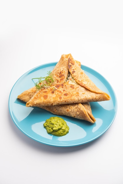 Envoltura triangular de Paratha con relleno de pollo a la patata, servido con chutney verde, comida india