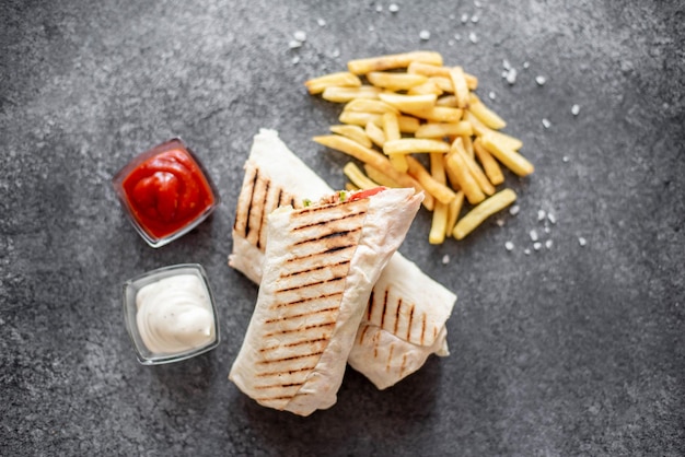 Envolturas de burrito con pollo y verduras y papas fritas sobre fondo de piedra