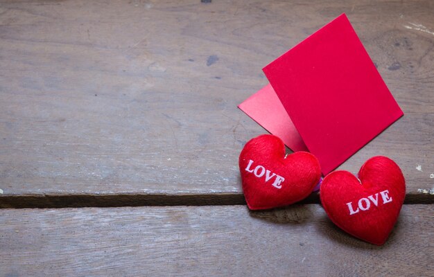 envolvente roja con almohada de corazón de forma sobre el amor de texto y sobre fondo de madera