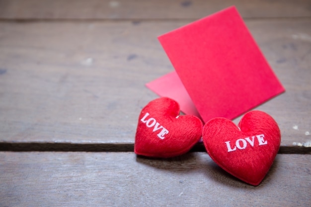 envolvente roja con almohada de corazón de forma sobre el amor de texto y sobre fondo de madera