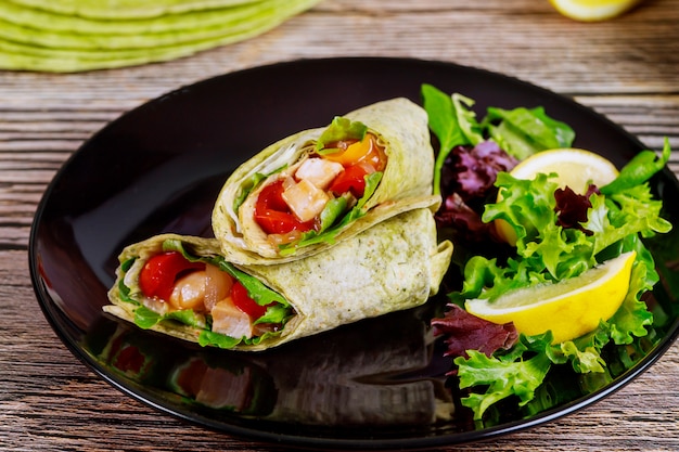 Envuelva con pollo a la parrilla y vegetales en un plato con ensalada verde y limón