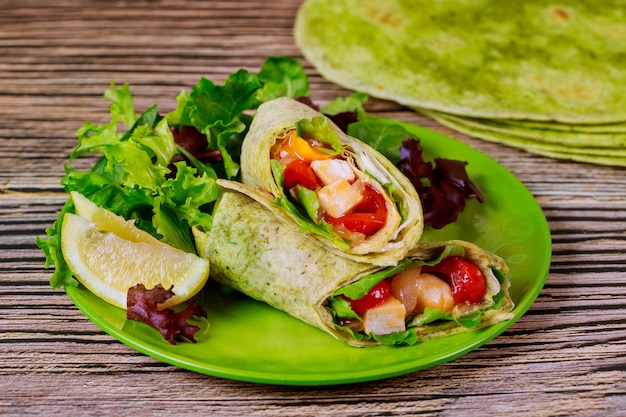 Envuelva con pollo a la parrilla y vegetales en un plato con ensalada verde y limón.