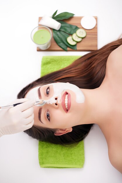 Epiléptico grave, aplicação de máscara de beleza facial para mulher jovem e bonita no salão spa