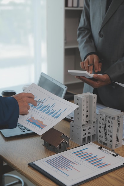 equilibrando el sector inmobiliario El agente inmobiliario está explicando el estilo de la casa para ver el diseño de la casa y el acuerdo de compra Casa de madera en una oficina moderna