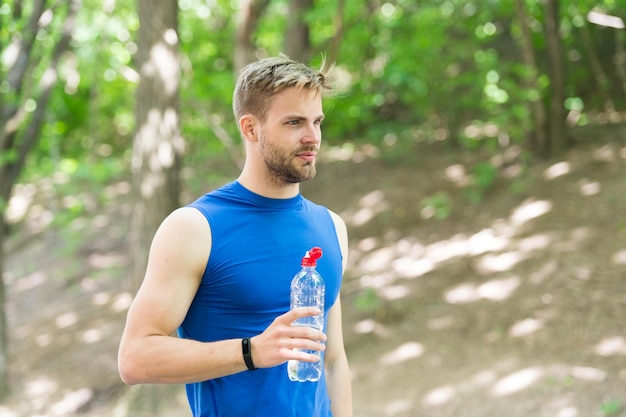 Equilibre su vida deporte y salud hombre en ropa deportiva beba agua refrescante bebida vitamínica después del entrenamiento hombre atlético con botella de agua Atleta beba agua después del entrenamiento cuidado hidratación corporal