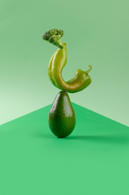Equilíbrio alimentar de vegetais verdes frescos em fundo de papel geométrico verde, abacate, pimenta e brócolis dieta vegetariana e vegana equilibrando conceito de comida criativa, espaço de cópia
