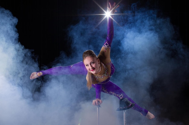 Equilibrio manual sobre bastones Cuerpo flexible de niña Actuación de una gimnasta aérea en un circo