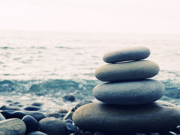 Equilíbrio, paz de espírito, pedras de tamanhos diferentes formam uma pirâmide, pirâmide de pedras em Pebble Beach, simbolizando estabilidade, zen, harmonia, equilíbrio. Profundidade superficial de campo.