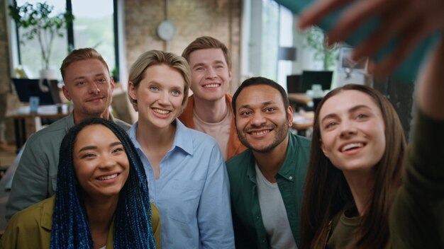 Equipa corporativa fazendo selfie de pé no escritório de perto colegas de trabalho felizes rindo