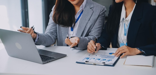 Equipa de negócios dois colegas discutindo novos dados de gráficos financeiros do plano na mesa do escritório com laptop e tablet digital