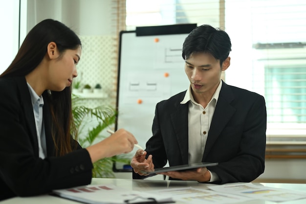 Equipa de negócios usando tablet digital e discutindo a estratégia do projeto no espaço de escritório de co-working