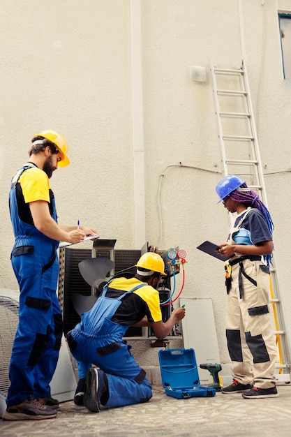 Equipa diversificada de técnicos certificados a trabalhar no exterior, a verificar se há filtros de ar obstruídos a dificultar o fluxo de ar da unidade HVAC, fazendo com que o sistema de refrigeração trabalhe mais e consuma mais energia