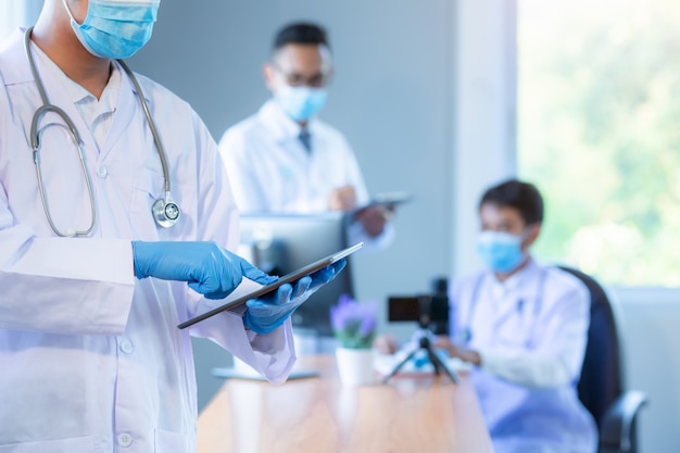 Equipa médica asiática que veste o conceito médico da reunião da equipe da rede da tecnologia das máscaras.