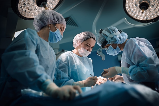 Foto equipa médica na sala de operações, fundo escuro.