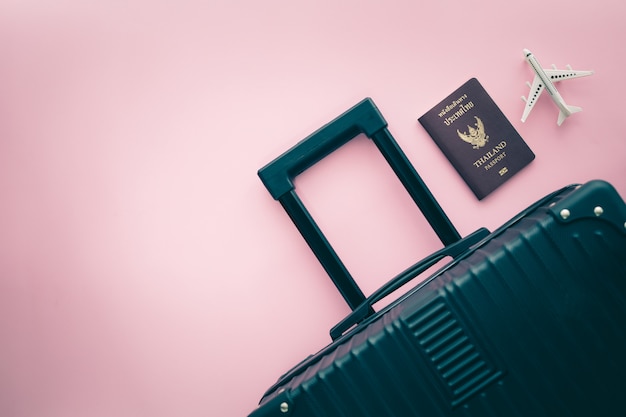 Equipaje negro, pasaporte tailandés y modelo de avión blanco sobre fondo rosa para el concepto de viaje y viaje