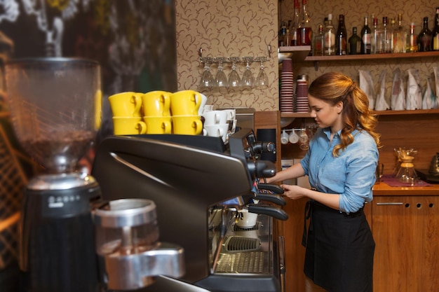 equipamento, cafeteria, pessoas e conceito de tecnologia - mulher barista fazendo café por máquina de café expresso no café bar ou cozinha do restaurante