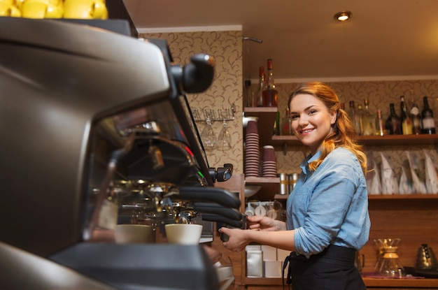 equipamento, cafeteria, pessoas e conceito de tecnologia - mulher barista fazendo café por máquina no café bar ou cozinha do restaurante