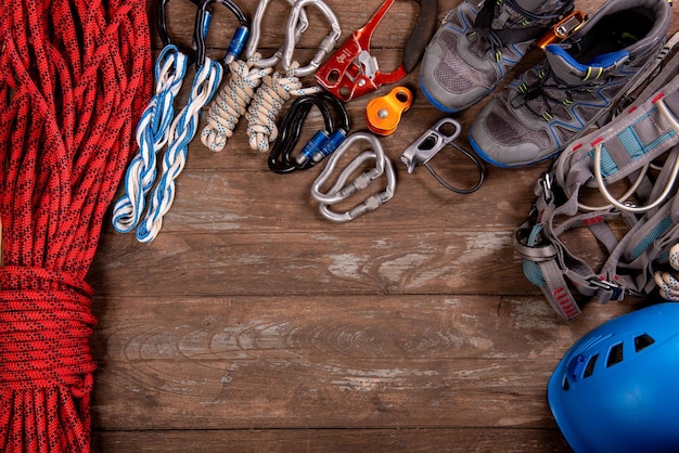 Equipamento de escalada para montanhismo e caminhada capacete martelo mosquetão trekking sapatos e outros na vista superior de fundo de madeira