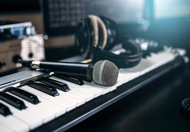 Equipamento de estúdio de música profissional, closeup. Teclado musical, microfone e fones de ouvido.