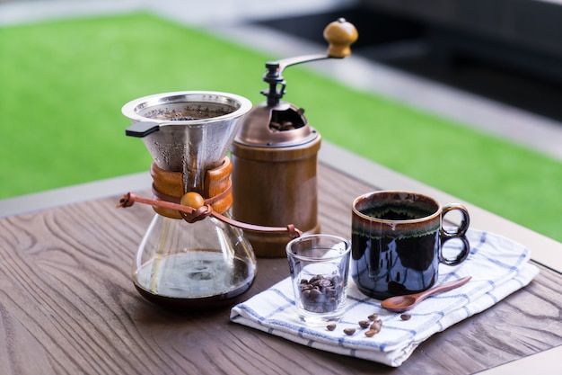 Equipamento de gotejamento de café situado na mesa de madeira.