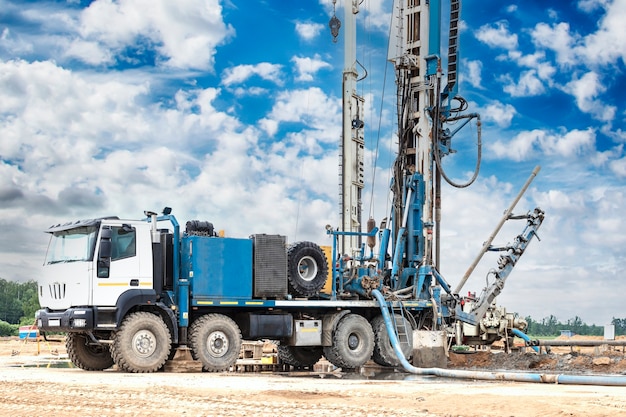 Equipamento de perfuração em um campo sob um céu azul nublado. Perfuração de poços profundos. Exploração geológica. Exploração mineral.