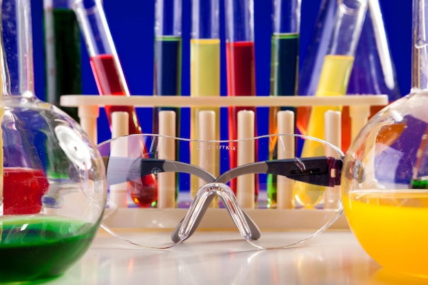 Equipamento de química em uma mesa sobre fundo azul. Vidraria e equipamentos de biologia