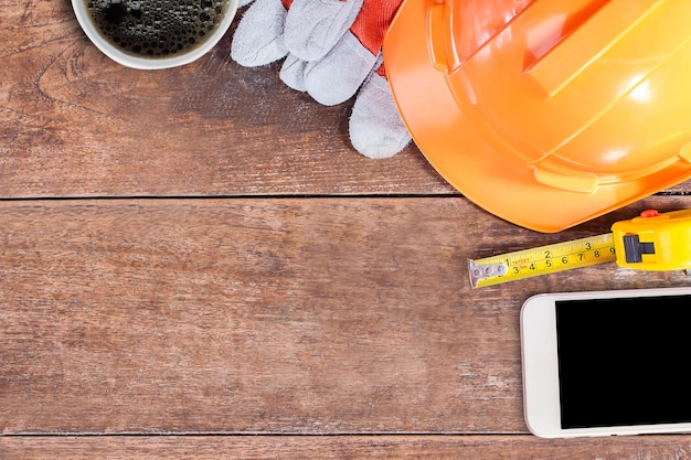 Equipamento de segurança de construção e caderno em branco ou bloco de notas na mesa de madeira