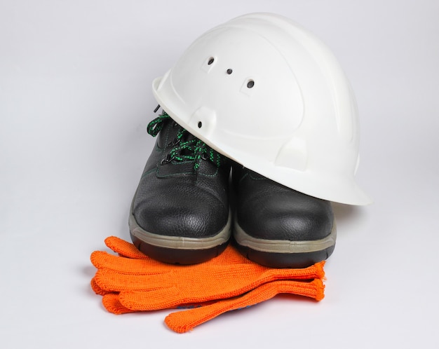 Foto equipamento de segurança em um fundo branco. capacete de construção, botas de couro de trabalho, luvas em um fundo branco.