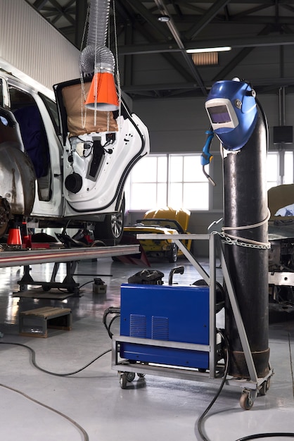 Foto equipamento de solda em uma estação de reparo do carro, capacete pendurado em um tanque de gasolina, ninguém