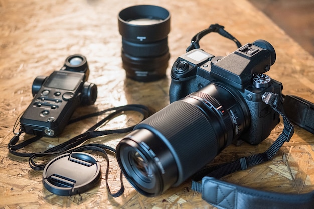 Foto equipamento fotográfico e câmera em um close-up da mesa de madeira. câmera digital moderna