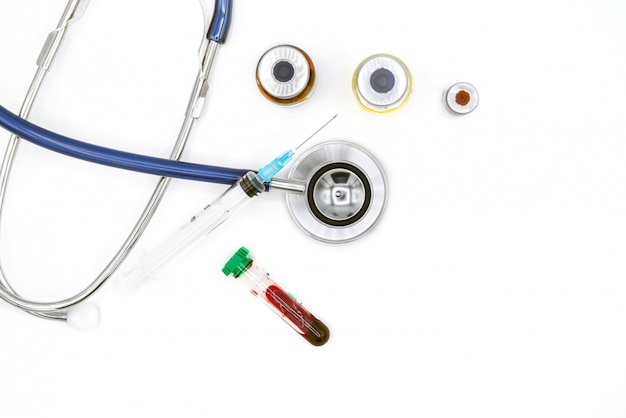 Equipamento médico na mesa do médico, em ampolas do estetoscópio e em seringa no fundo branco com espaço da cópia, close-up. Conceito de cuidados de saúde.