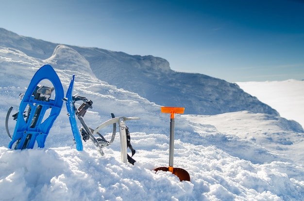 Equipamento para montanhismo no topo de uma montanha coberta de neve no fundo do sol. raquetes de neve, eixo de gelo, pá de avalanche, na geleira