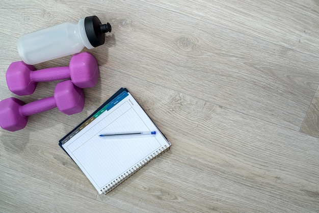 Equipamentos esportivos em forma de caderno de halteres de bolas de água e alças estão no chão