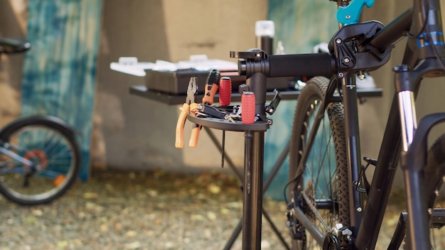 Equipamentos profissionais são usados para manutenção e reparo externo de bicicletas. A câmera captura diferentes ferramentas de trabalho especializadas configuradas para ajuste e restauração de bicicletas no quintal.