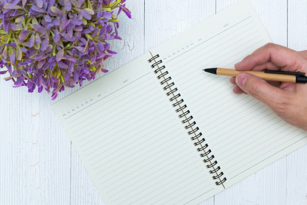 Equipe a escrita da mão na página vazia do papel do caderno com pena, materiais de escritório, vista superior.