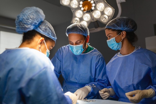 Equipe cirúrgica realizando cirurgia no moderno centro cirúrgicoEquipe de médicos concentrando-se em um paciente durante uma cirurgiaEquipe de médicos trabalhando juntos durante uma cirurgia na sala de cirurgia