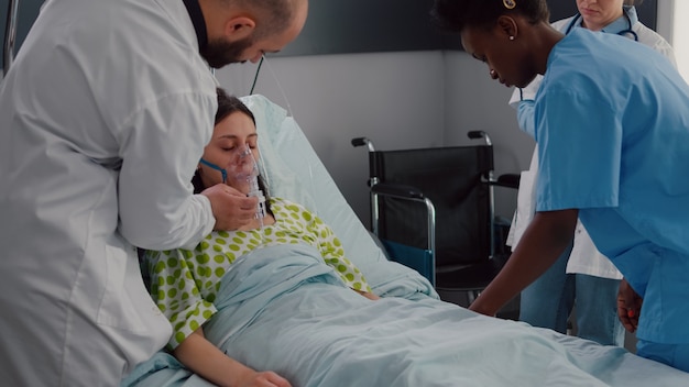 Equipe clínica monitorando mulher doente colocando máscara de oxigênio e analisando doença respiratória