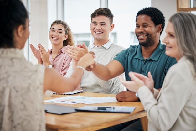 Equipe criativa em reunião batendo palmas e dando um aperto de mão para uma promoção e boas-vindas ao grupo profissional e corporativo de diversidade comemorando o trabalho em equipe bem-sucedido na sala de reuniões do escritório corporativo