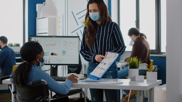 Equipe da empresa verificando gráficos financeiros usando máscara protetora